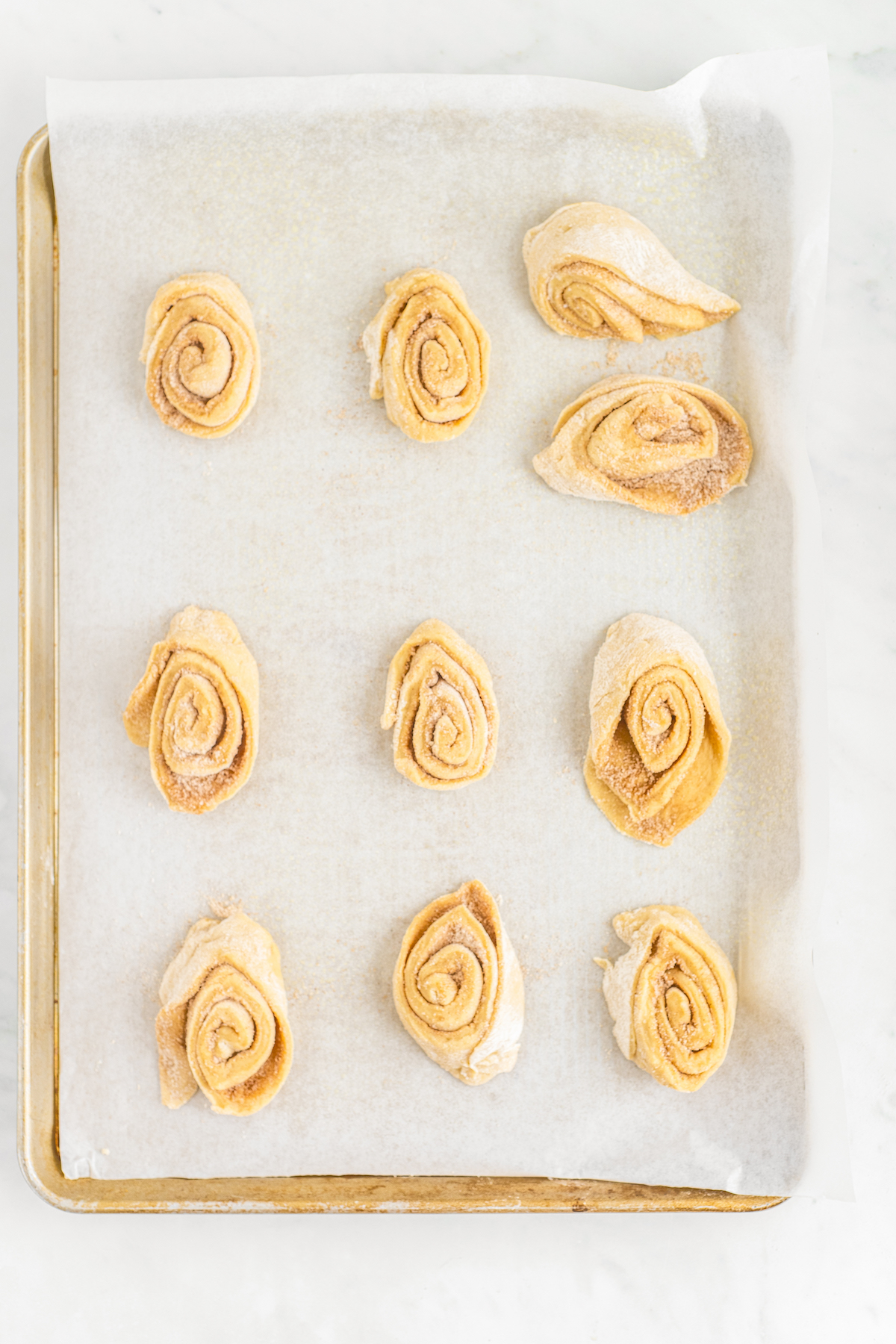 Unbaked sticky buns on a parchment-lined baking sheet.