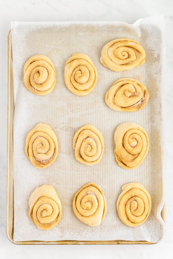 Risen honeybuns on a baking sheet.