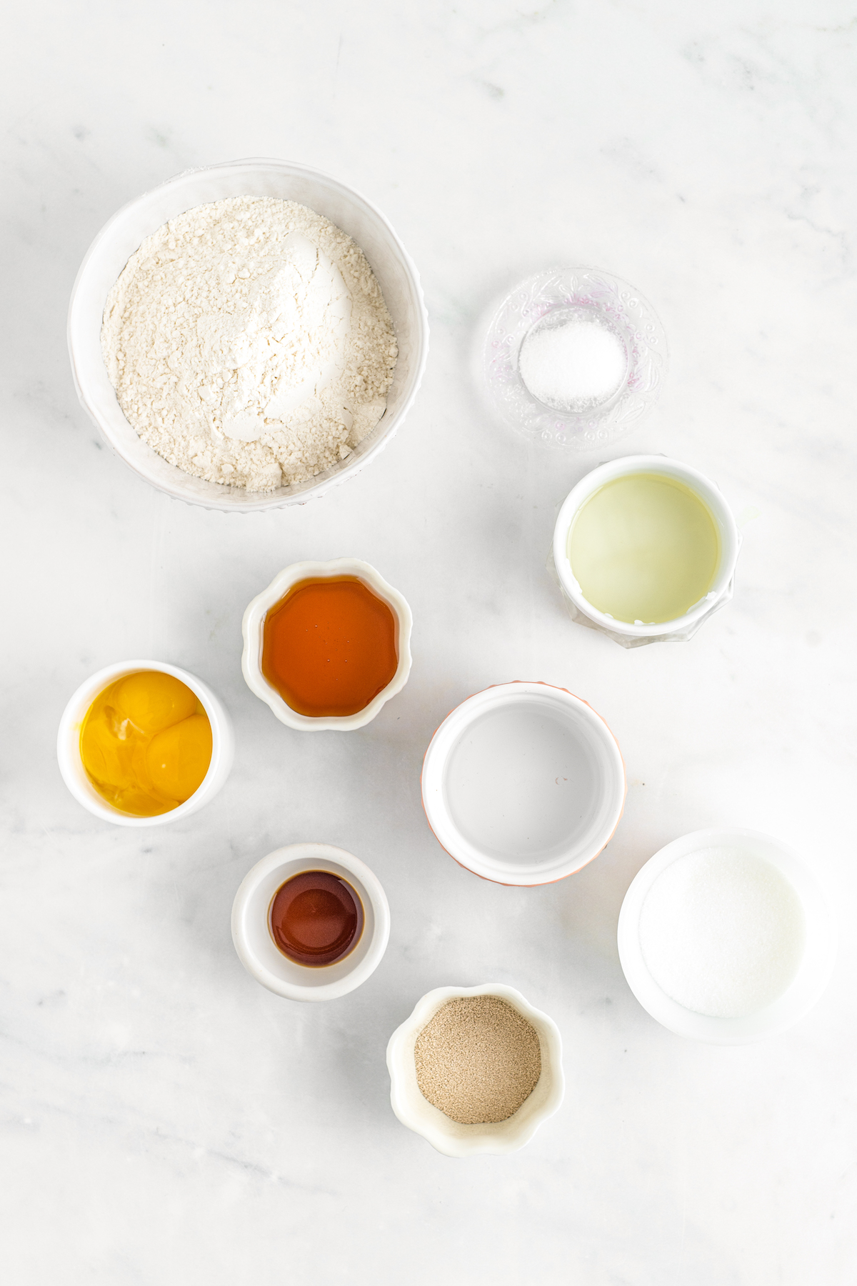 From top left: Flour, salt, melted shortening, egg yolks, vanilla, water, honey, yeast, sugar.