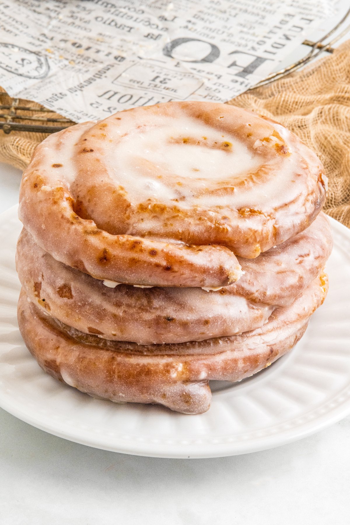 Three honey buns stacked on a plate.