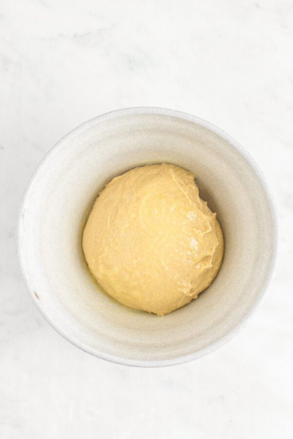 A ball of dough in a white mixing bowl.