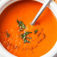 Close up shot of creamy blended soup garnished with fresh chopped basil.