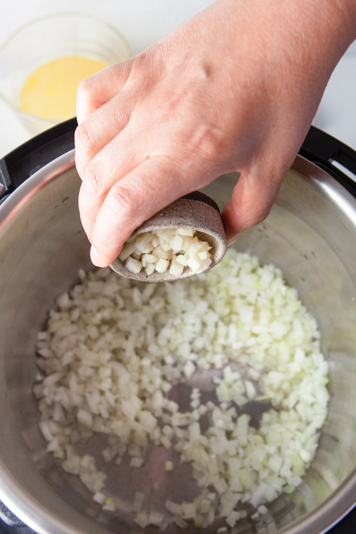 Adding garlic to onions cooking in an Instant Pot.