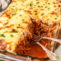 A casserole dish of baked spaghetti, with some of the casserole removed from the dish, revealing the layers.