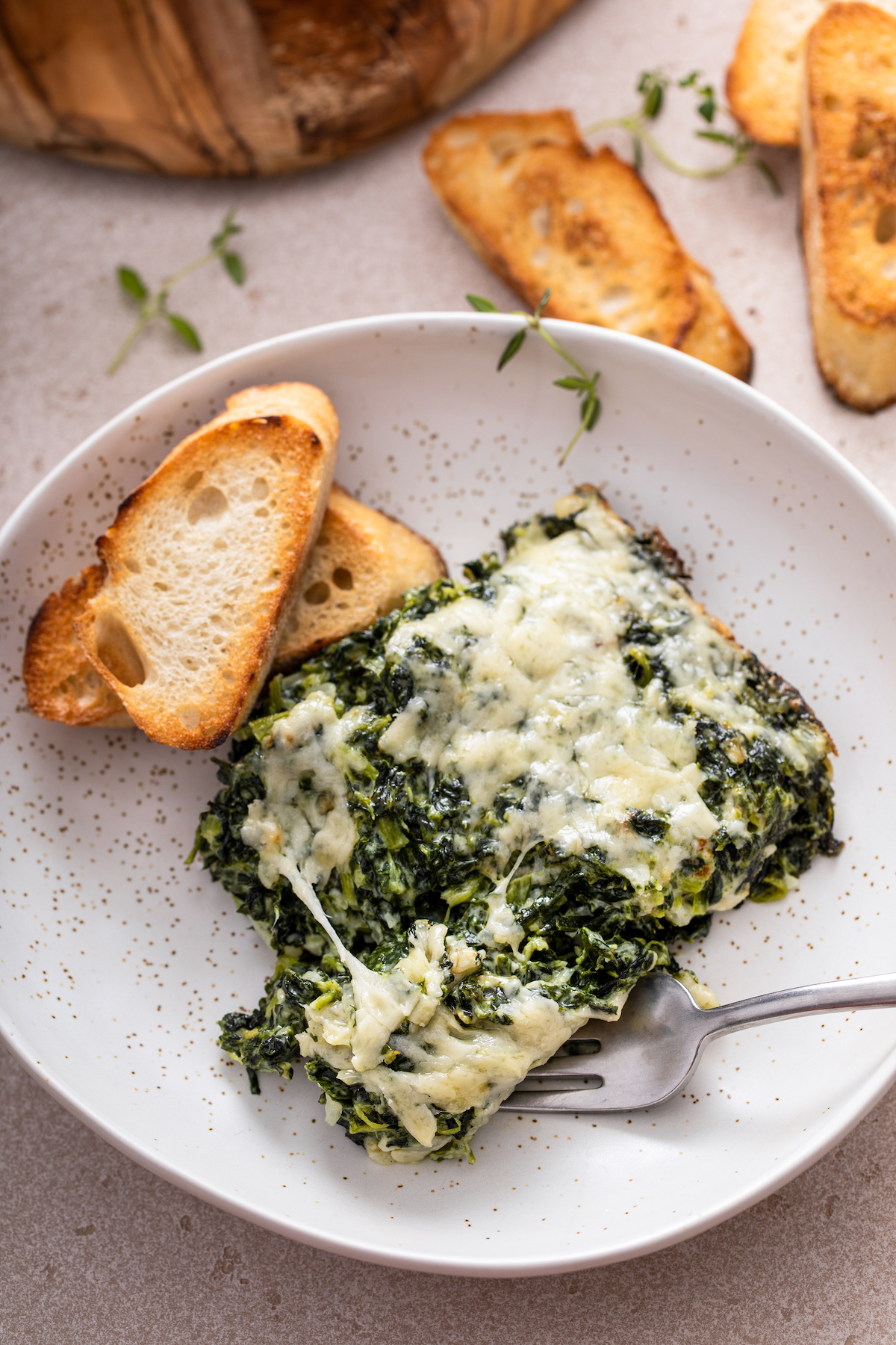 A serving of spinach gratin on a plate with a fork taking a bite.