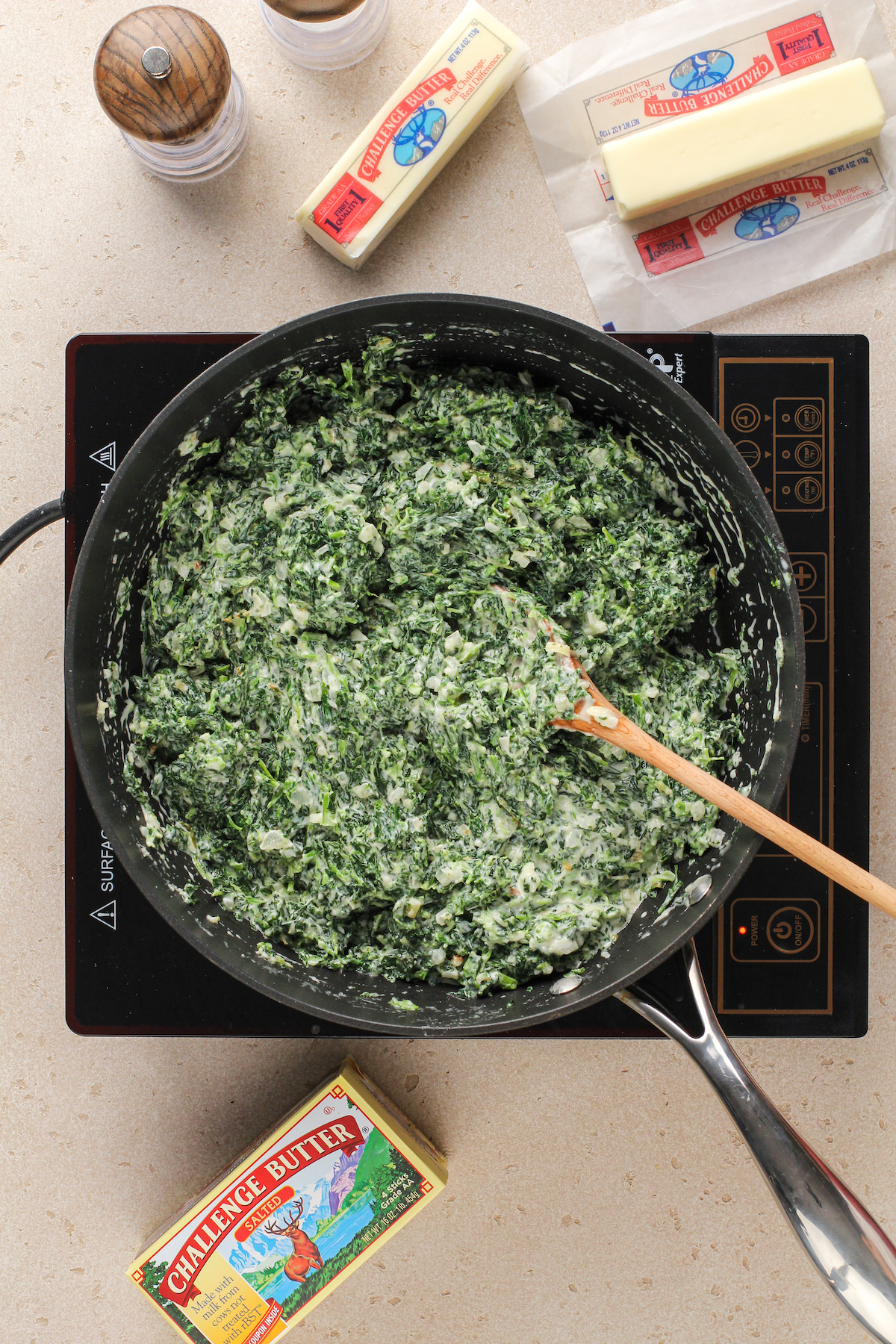 Creamed spinach in a skillet with a wooden spoon.