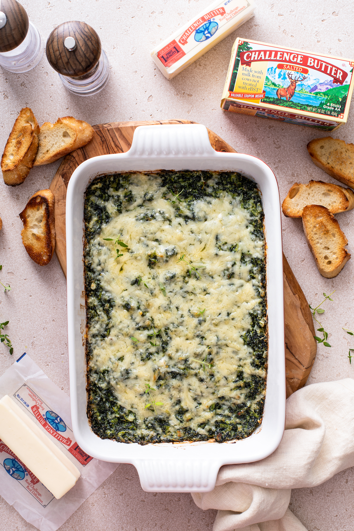 Spinach casserole in a baking dish with a tea towel and toasts.