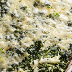 Spinach casserole in a baking dish with a spoon.