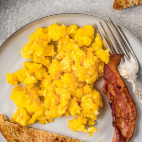 Scrambled eggs, toast and bacon on a plate.