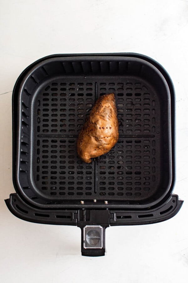 A baked sweet potato in an air fryer basket.
