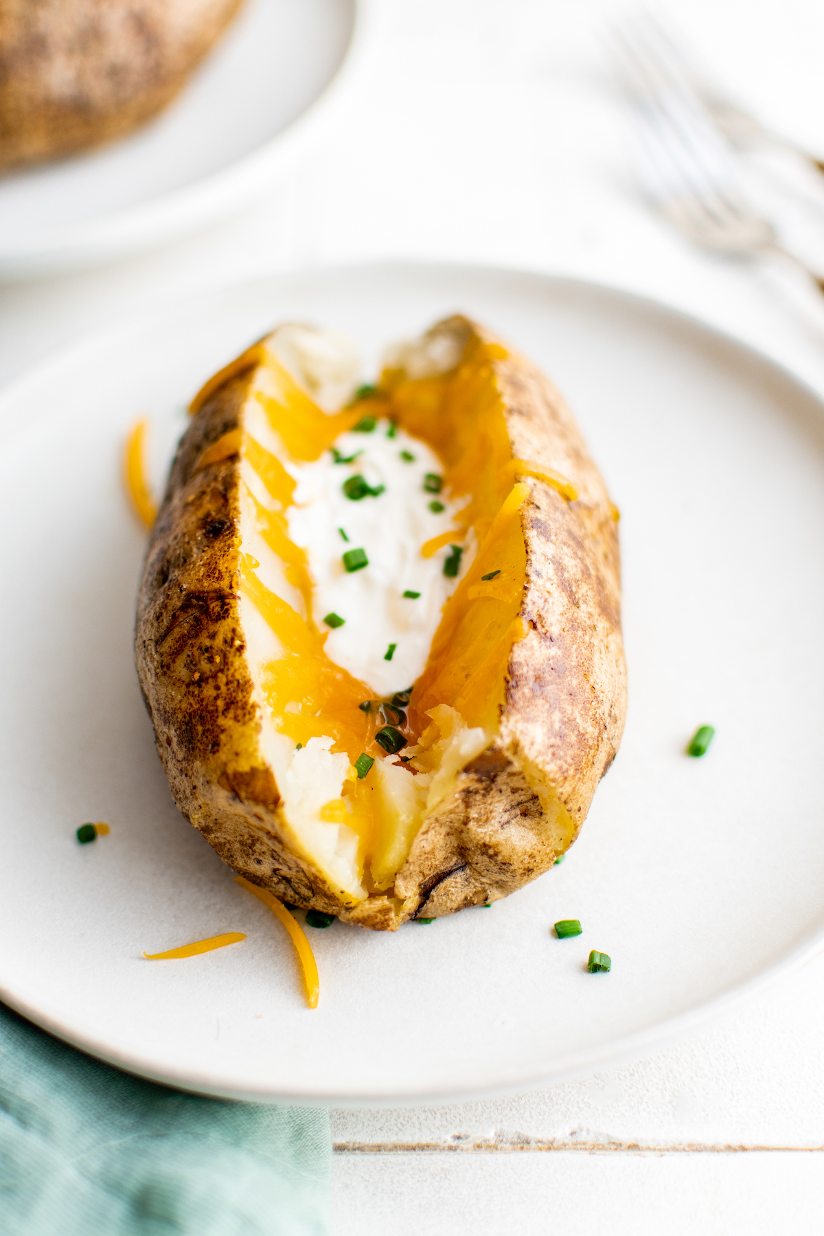 A roasted potato with melted cheese, sour cream, and chives.