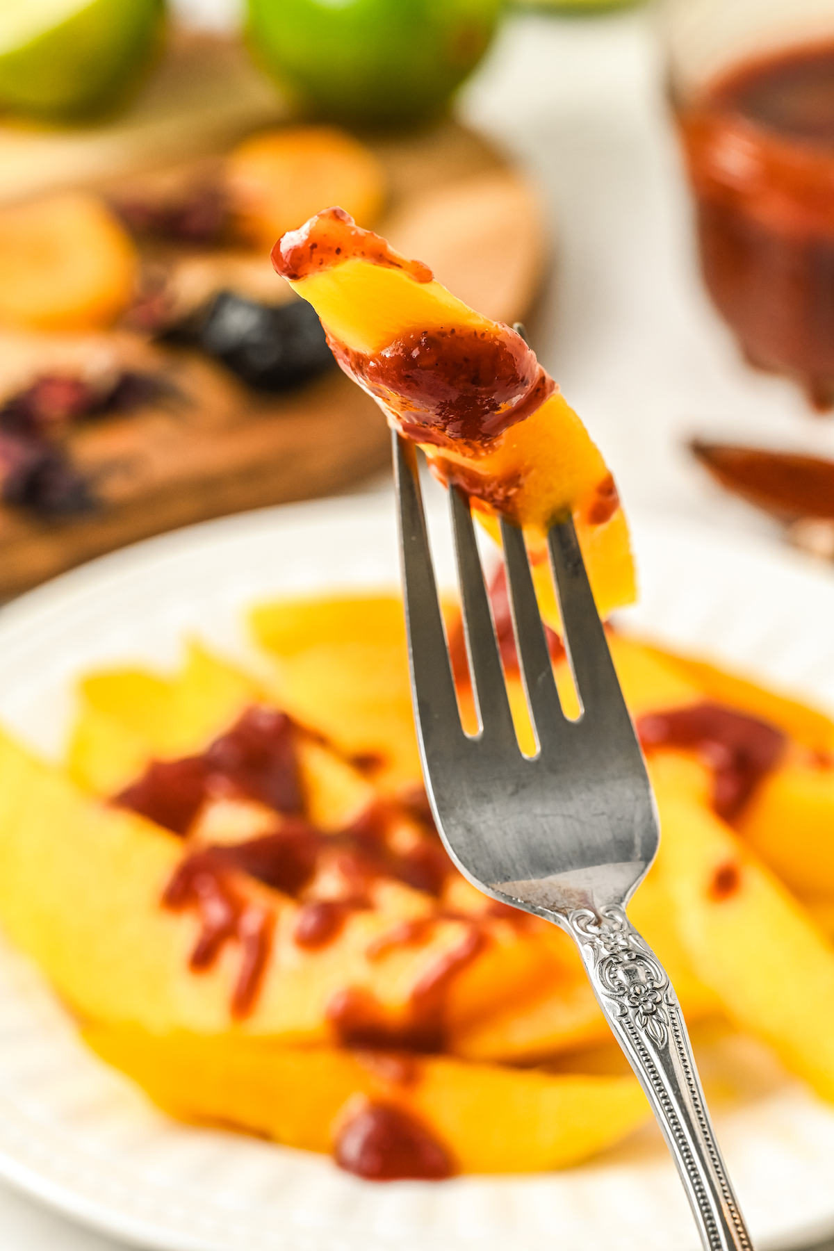 Holding up a slice of mango with a fork and homemade chamoy drizzle. 