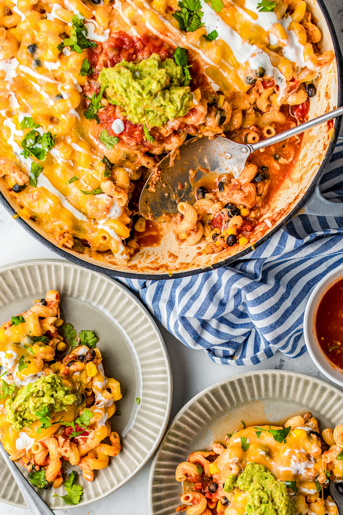 Cheesy Mexican Chicken Pasta in a skillet with two plates filled with servings.