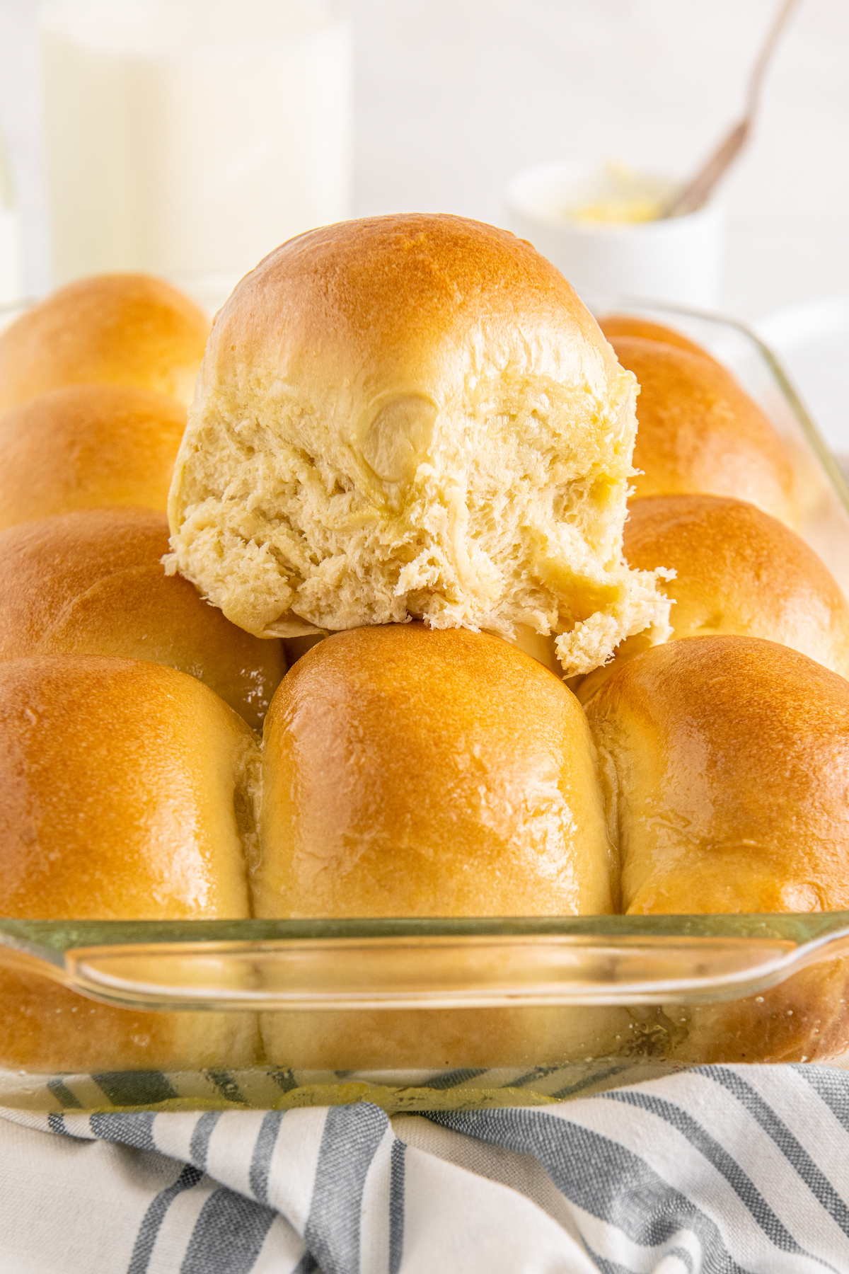 A pan of dinner rolls, with one removed from the pan and placed on top of the others.
