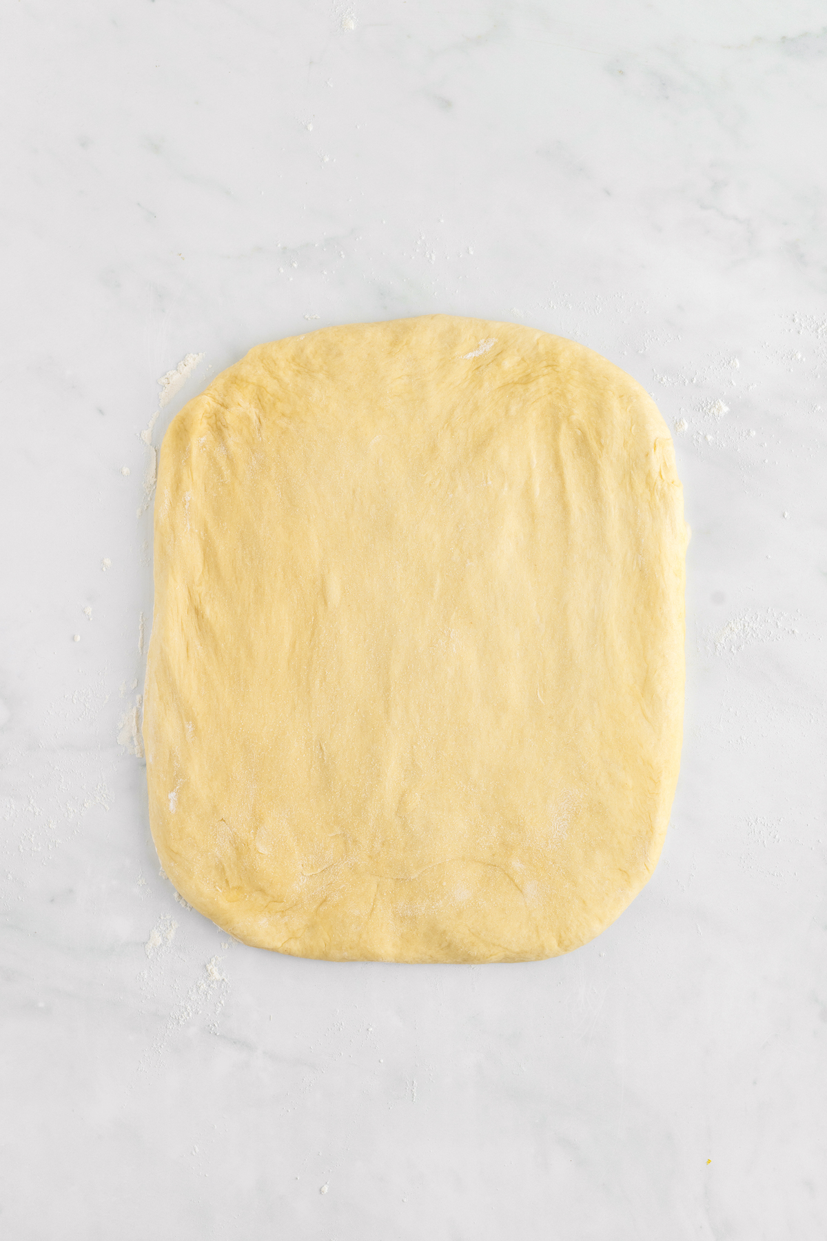 A rectangle of dough patted out on a work surface.