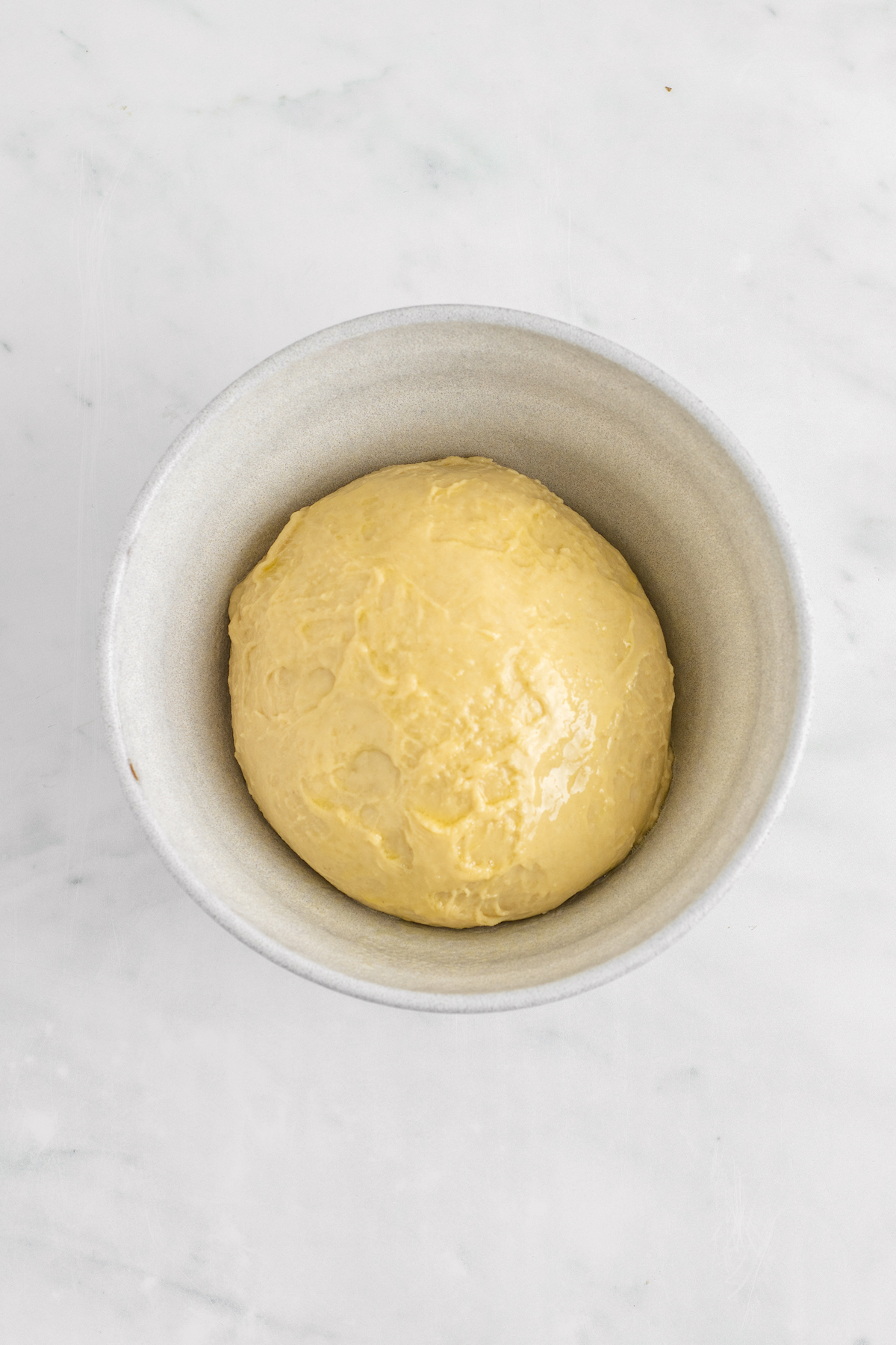 Dinner roll recipe dough in a white bowl.