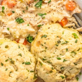 A bowl of southern chicken and biscuits with herbs.