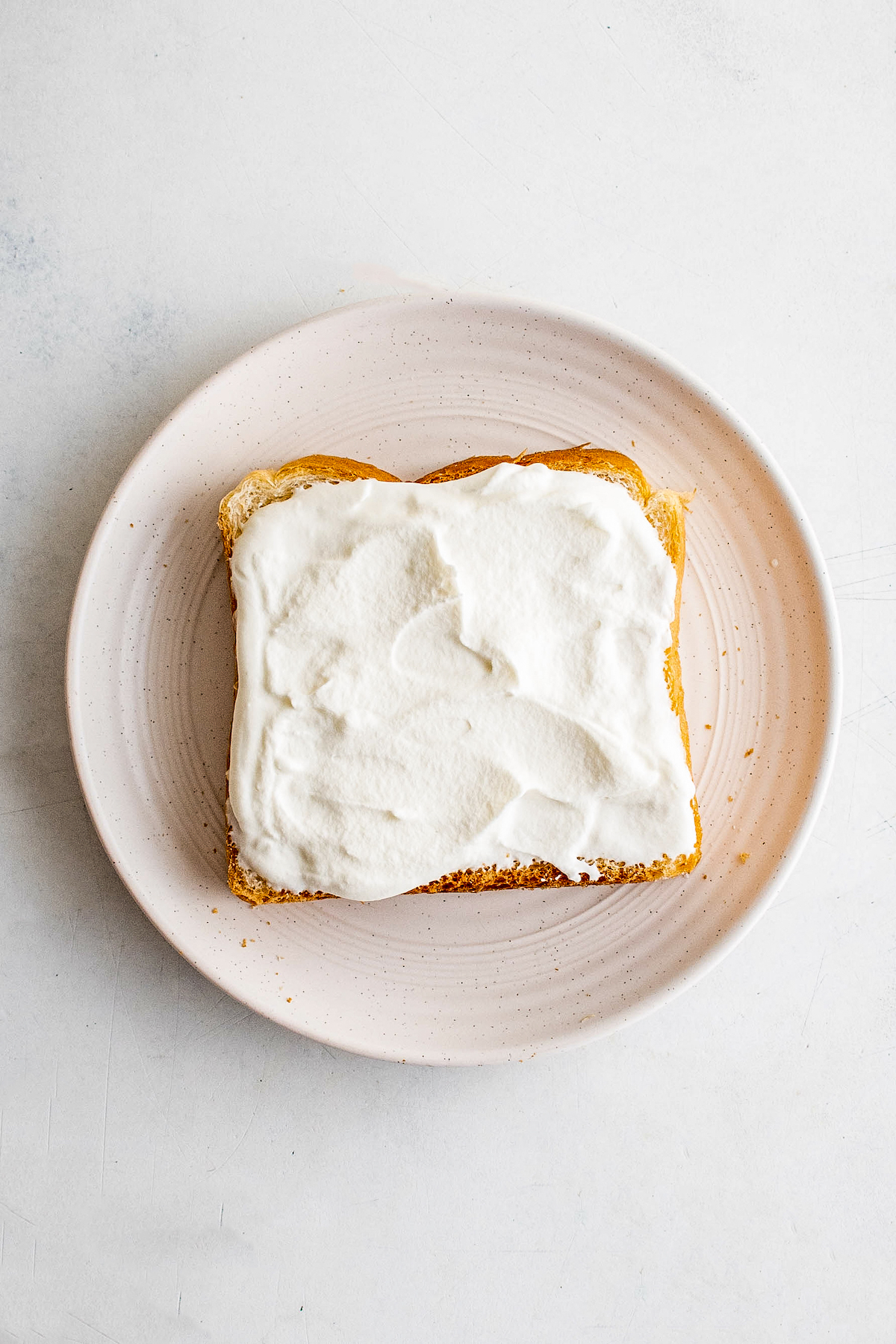Whipped cream spread on a piece of sandwich bread.
