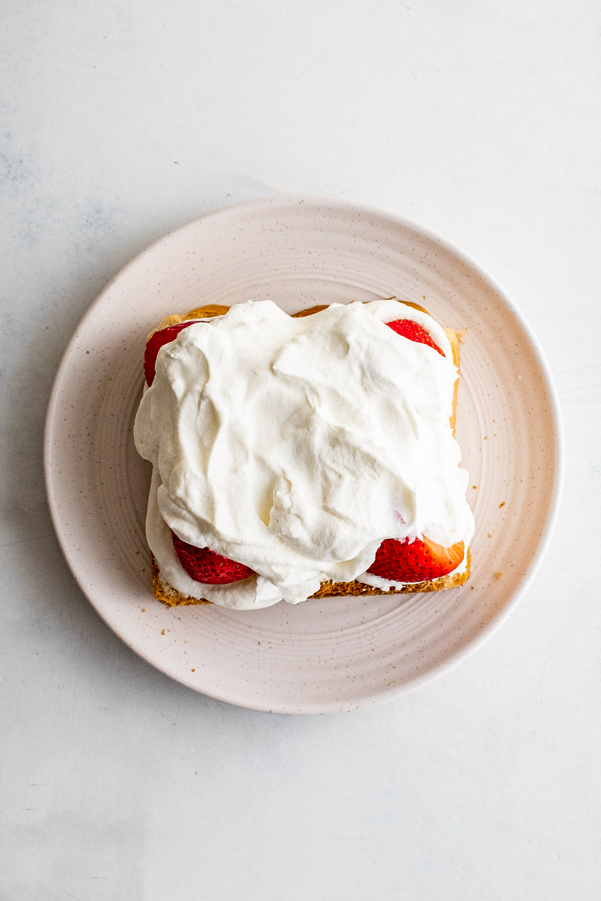 Bread topped with a layer of whipped cream, fruit, and more whipped cream.