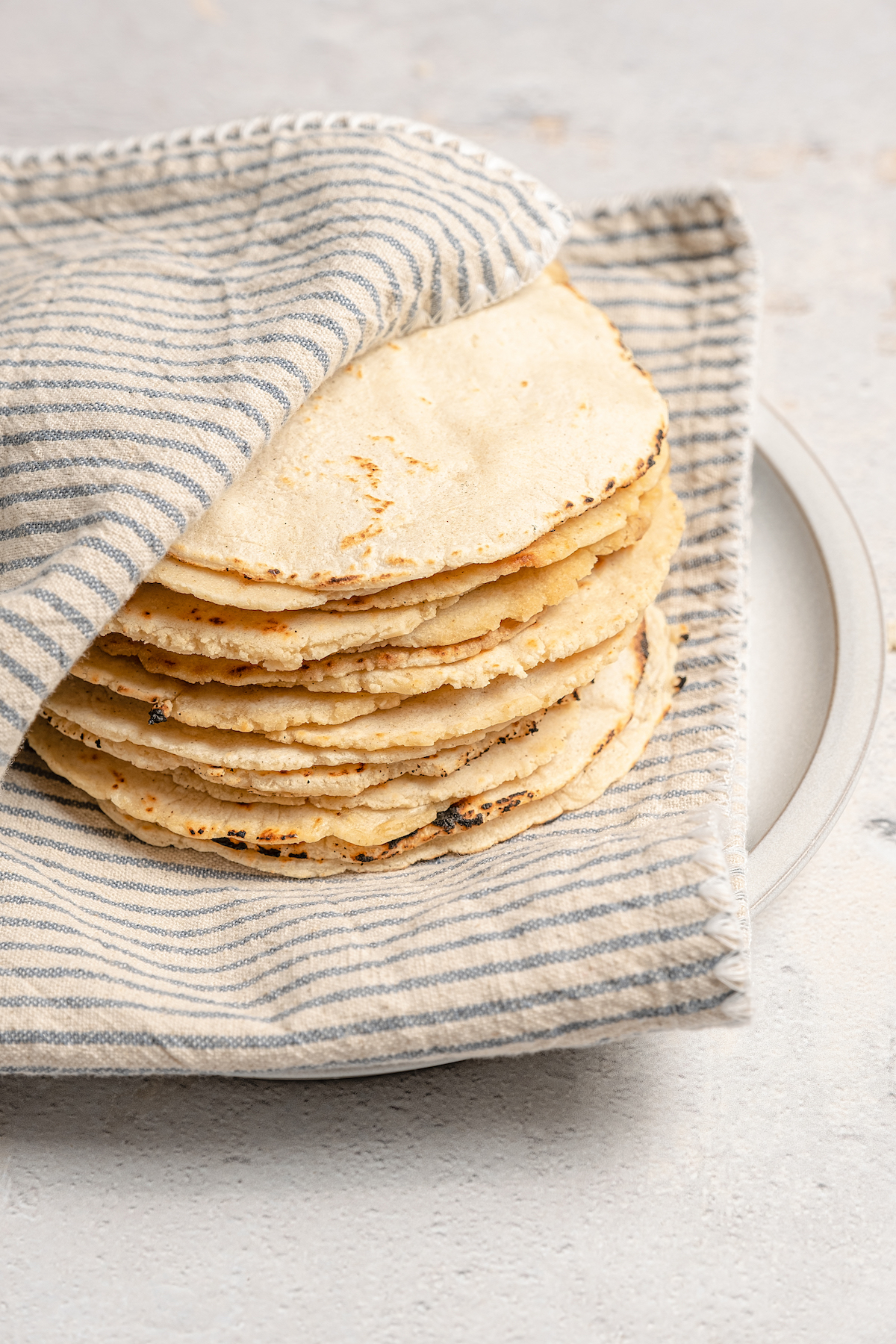 Stack of authentic corn tortilla recipe in a kitchen towel.