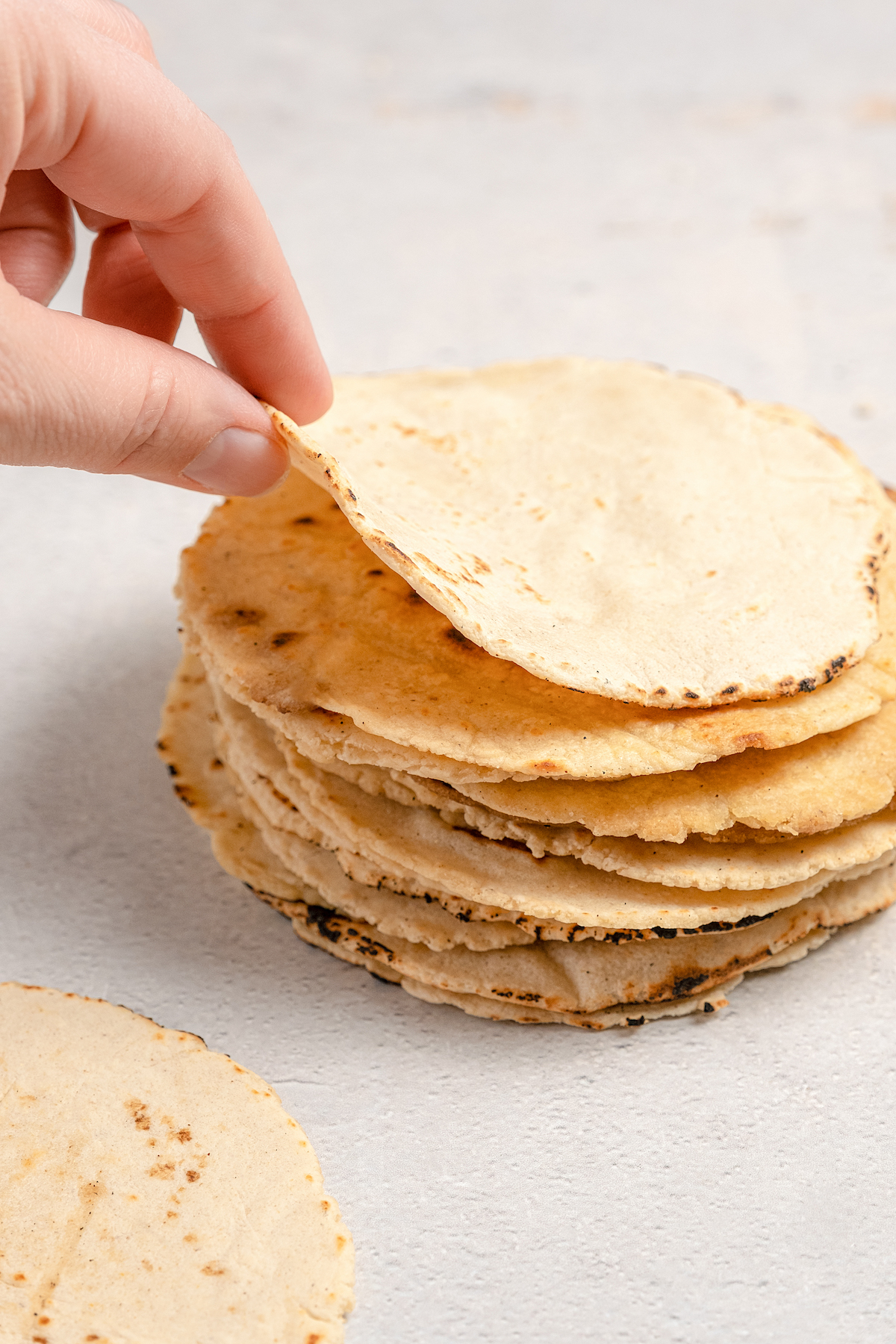 Lifting a tortilla from the stack.