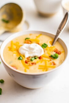 A bowl of instant pot potato soup with sour cream and other toppings.