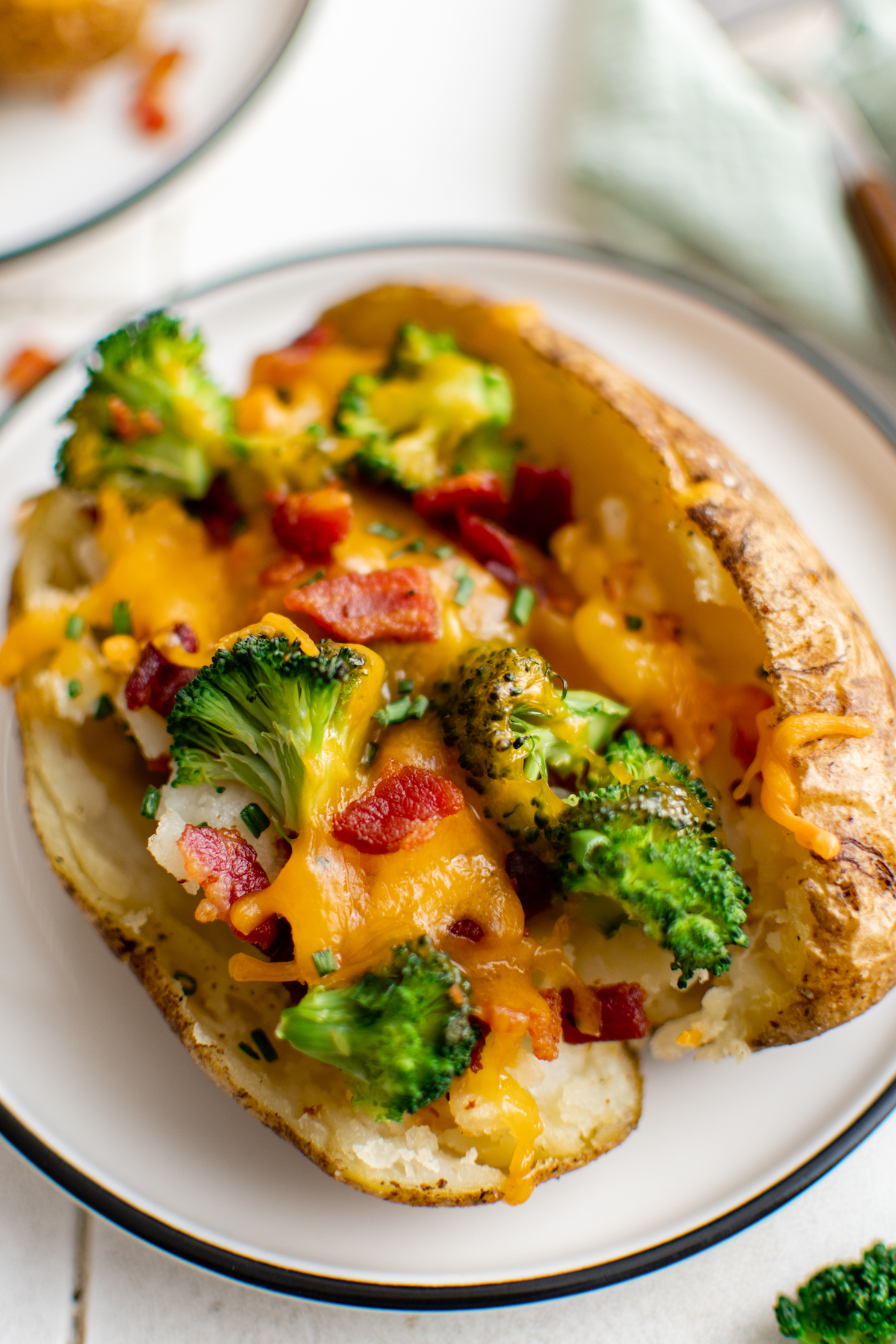 A single baked potato stuffed with broccoli and other toppings.