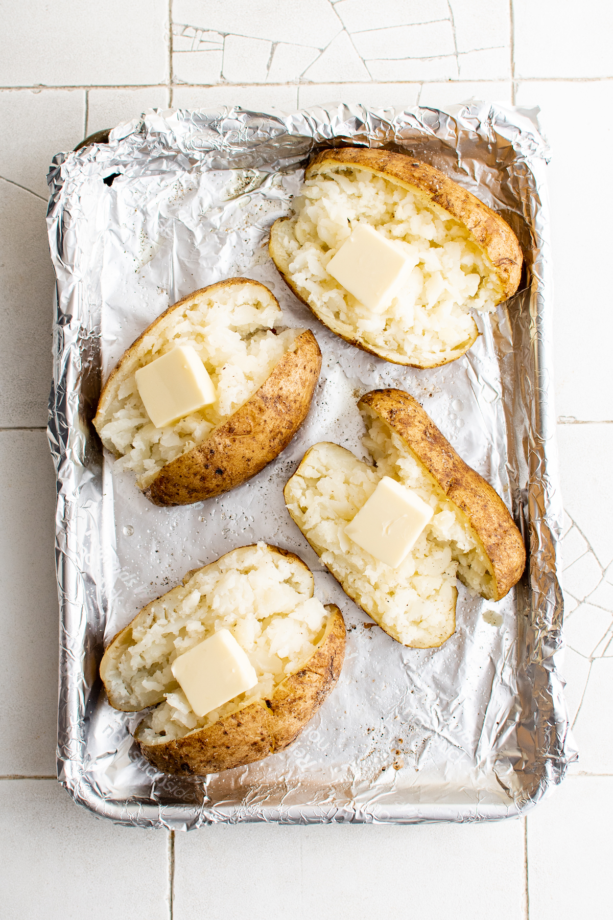 Baked potato recipe with butter on each potato.