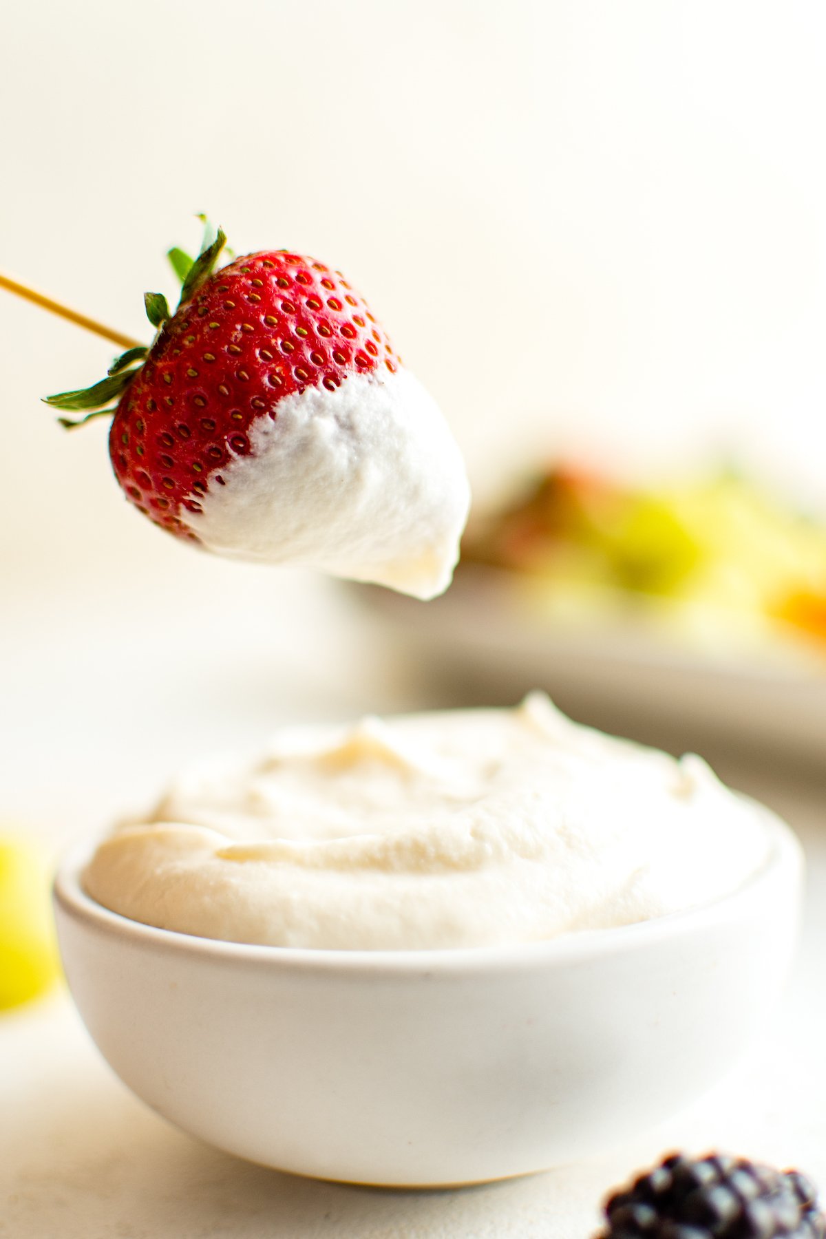 Dipping a strawberry in creamy sauce.