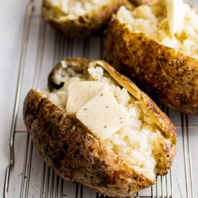 Microwave baked potatoes on a wire rack, cut in half and topped with butter.