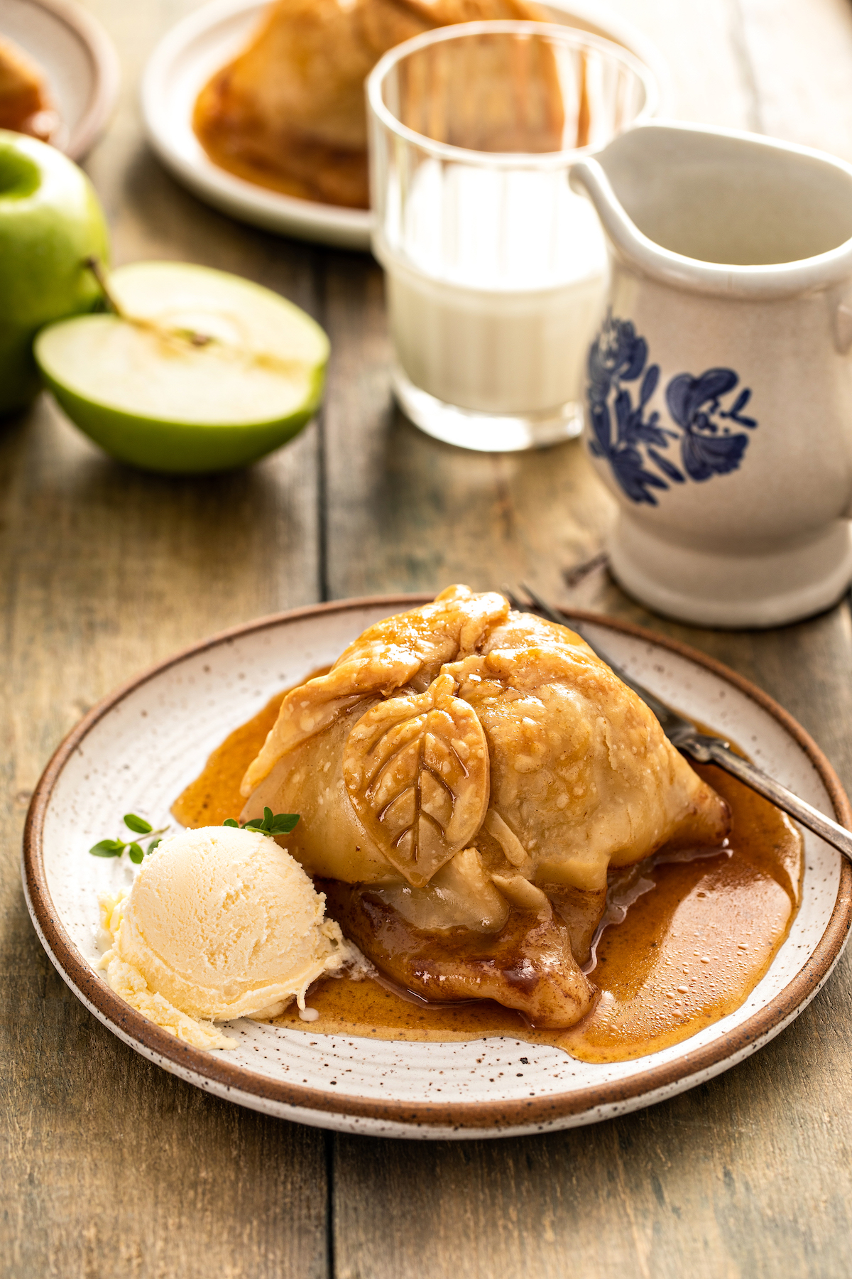 An apple dumpling with sauce on a small plate.