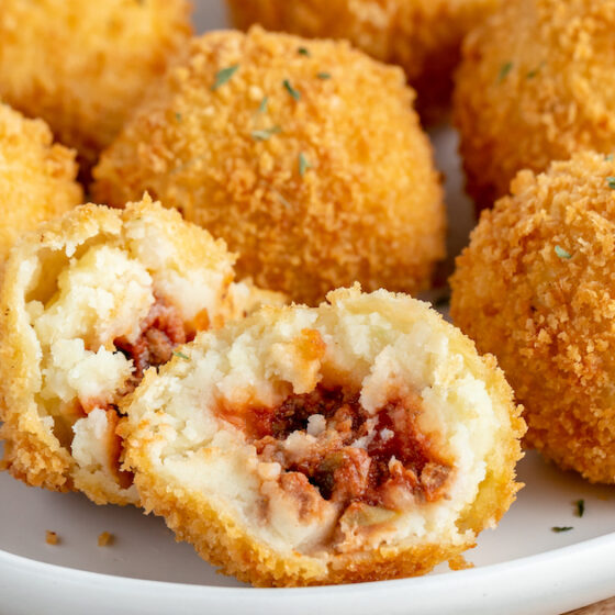 Papas Rellenas on a plate with one sliced in half to show the filling.