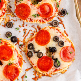 Homemade pizza bagels on a parchment-lined tray.