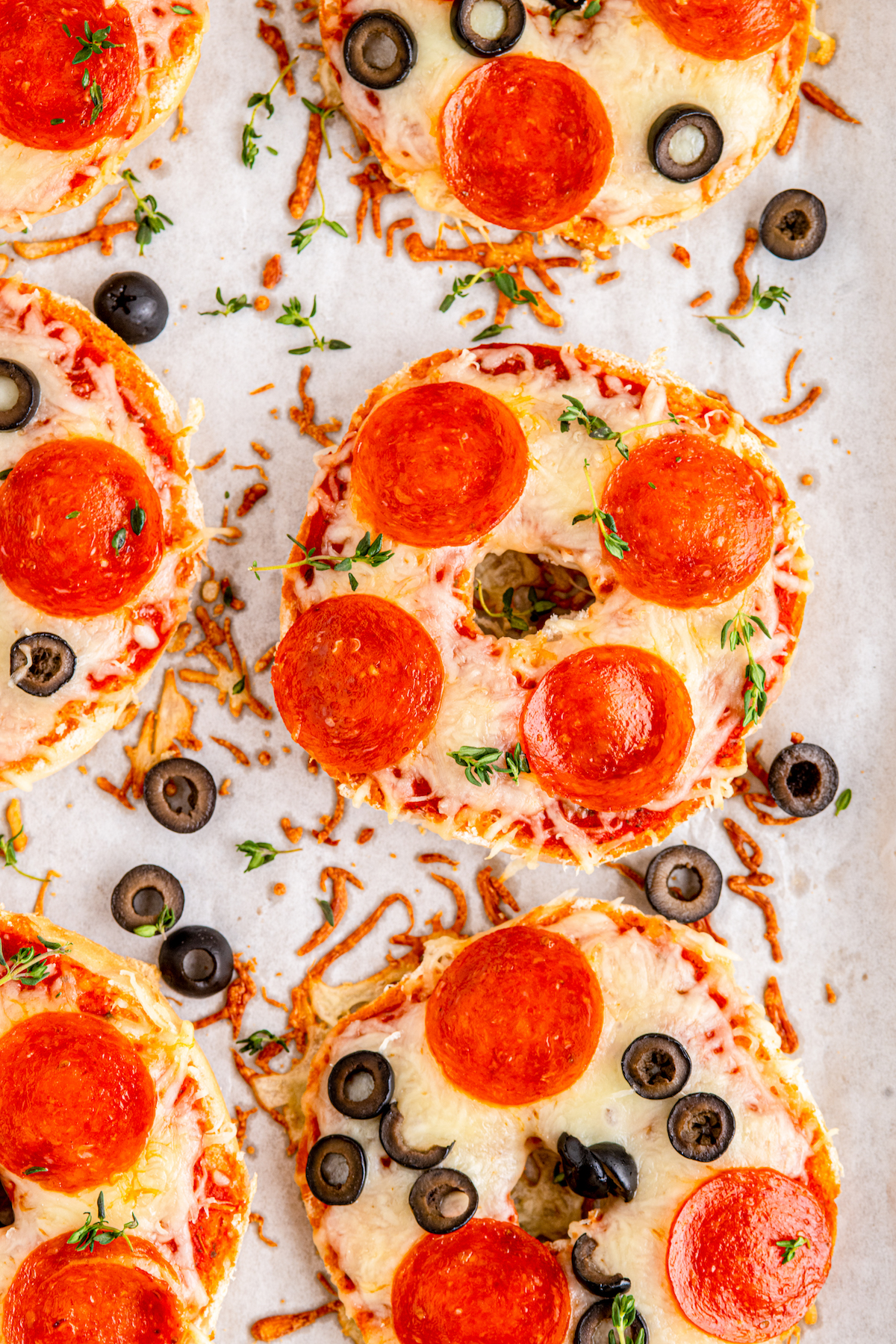 Close-up shot of pizza bagels, fresh out of the oven on a parchment-lined tray.