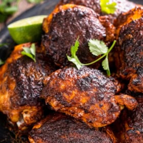 A platter filled with pollo asado chicken thighs with cilantro.