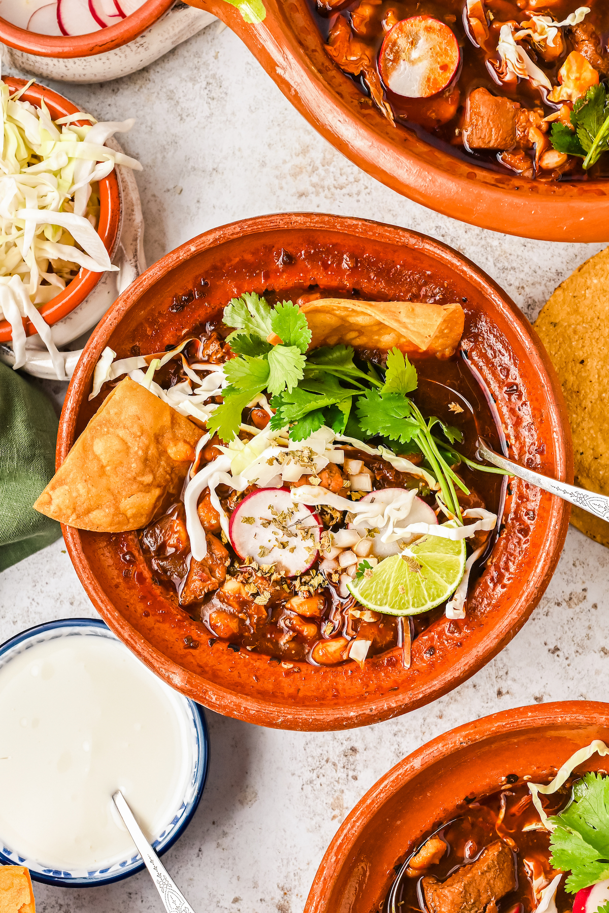 Red pozole with toppings in a bowl.