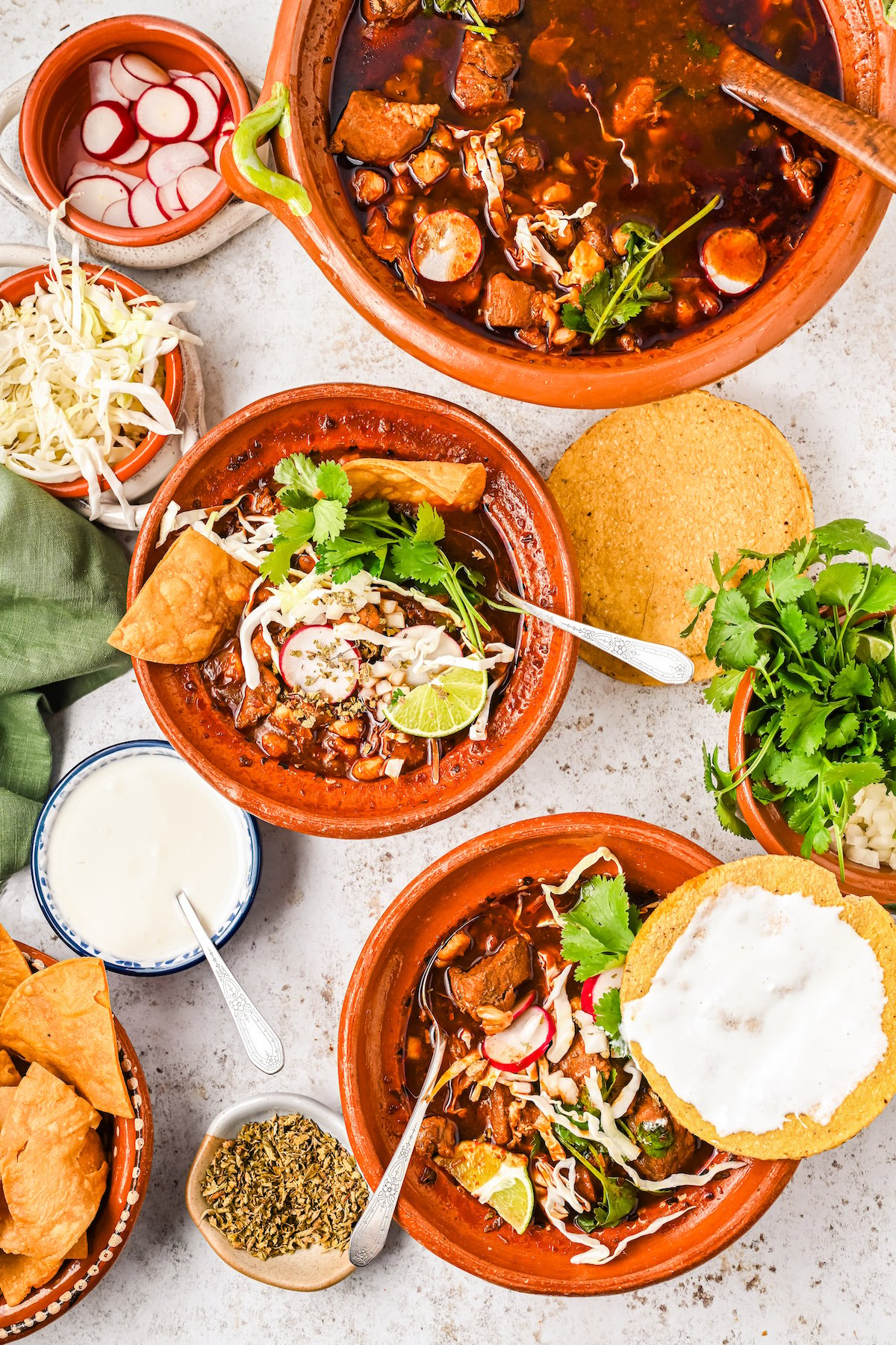 Bowls of red pozole with toppings.