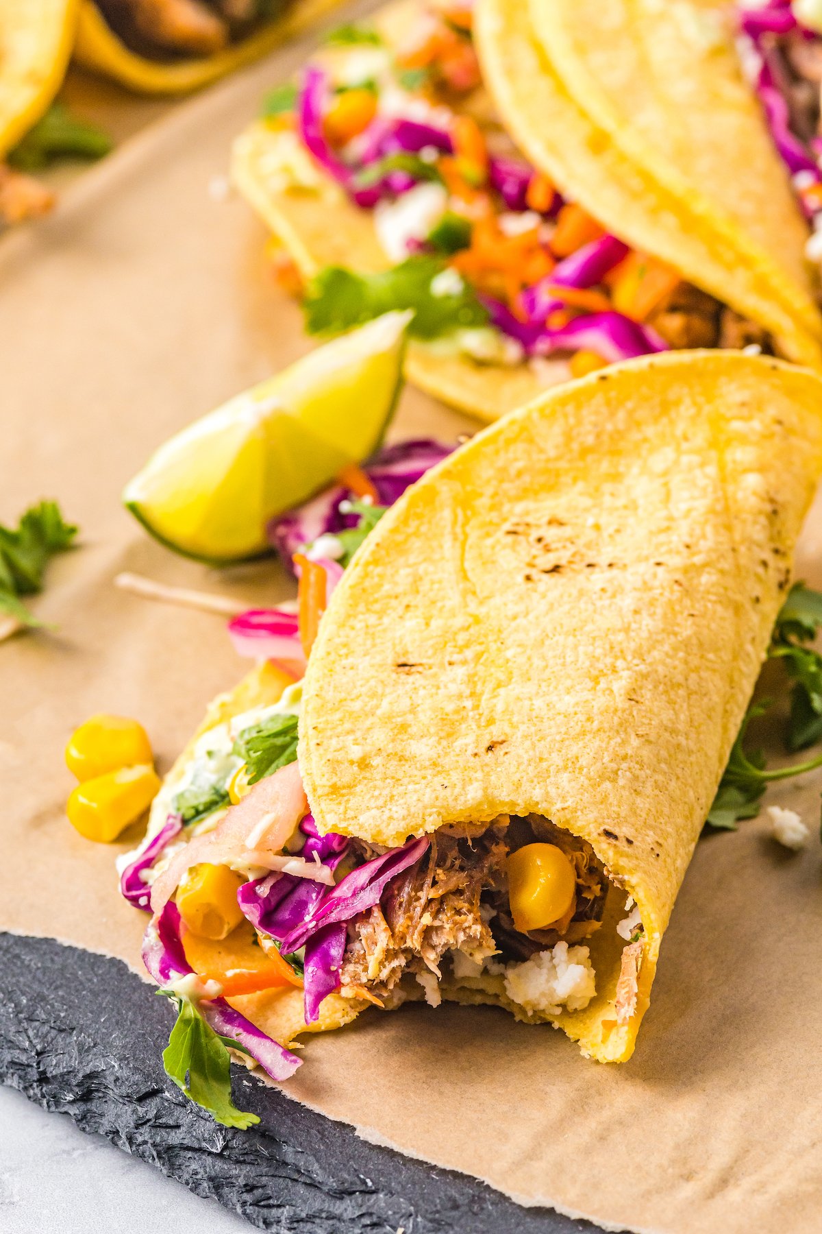A corn tortilla wrapped around a colorful filling of red cabbage coleslaw, pulled pork, and other ingredients.