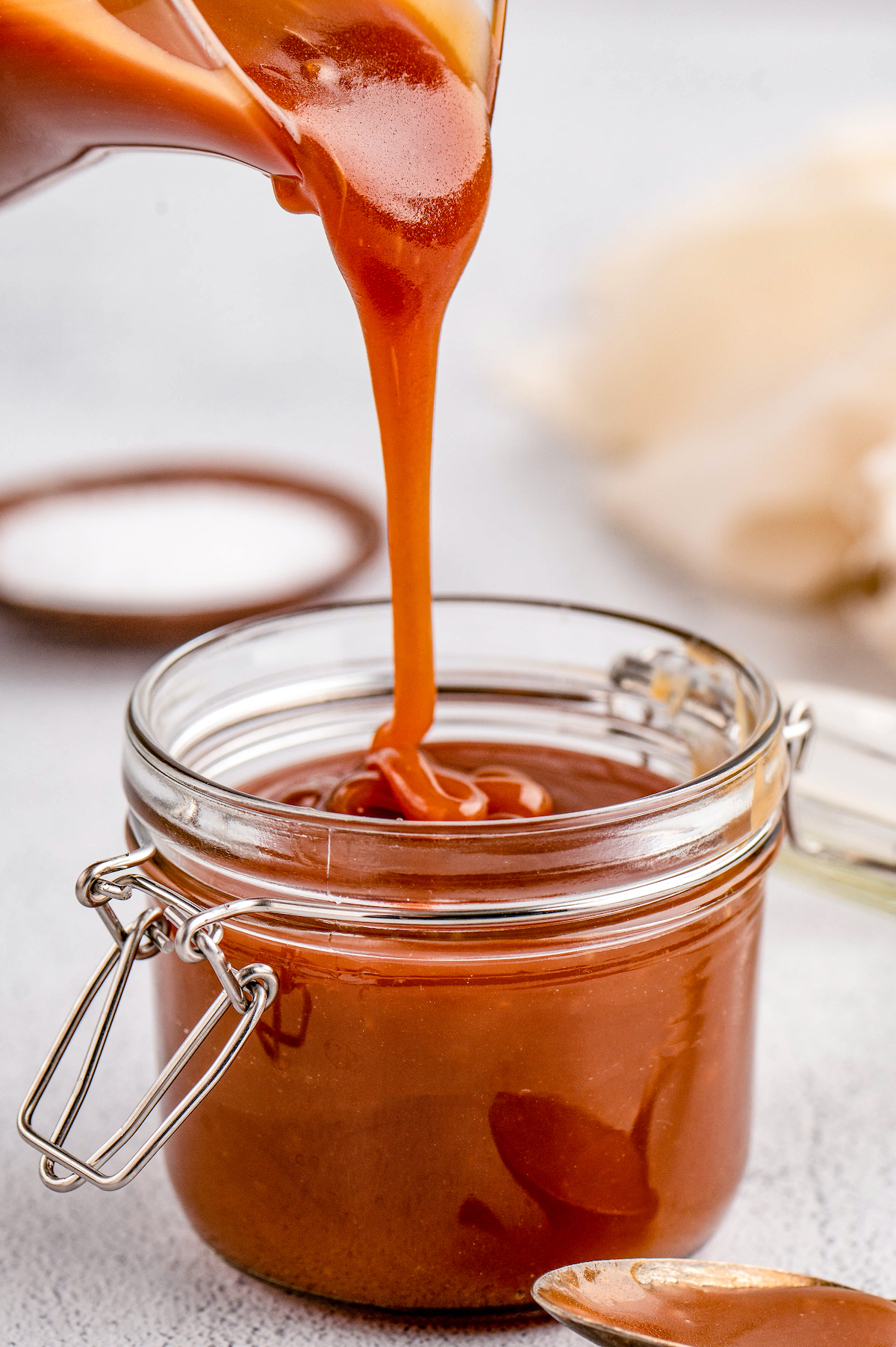 Pouring salted caramel into a glass jar.