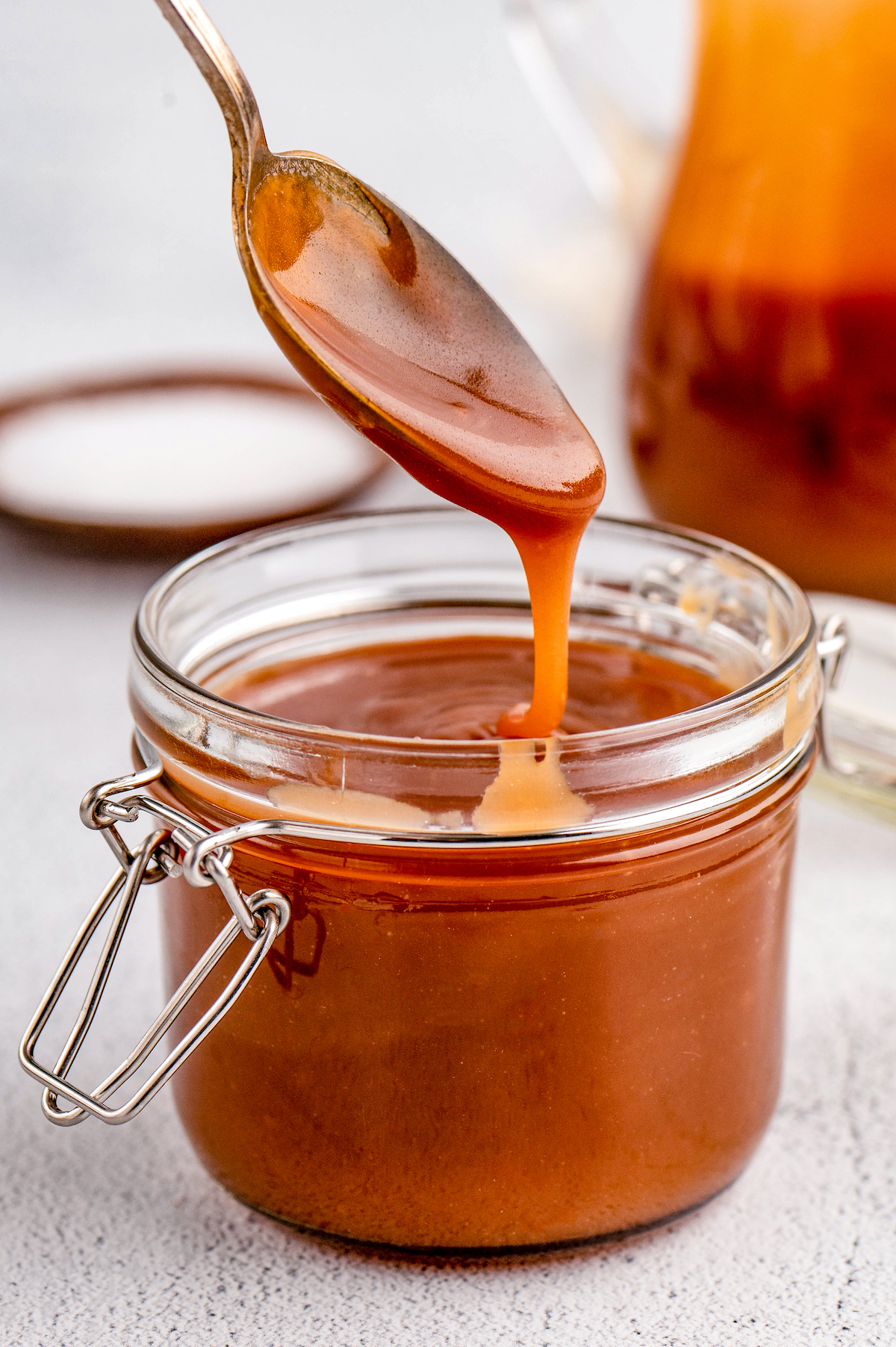 Adding salted caramel into a glass jar with a spoon.