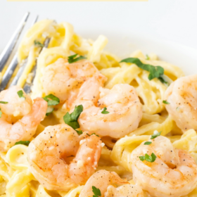 Shrimp on top of fettuccini Alfredo with parsley.