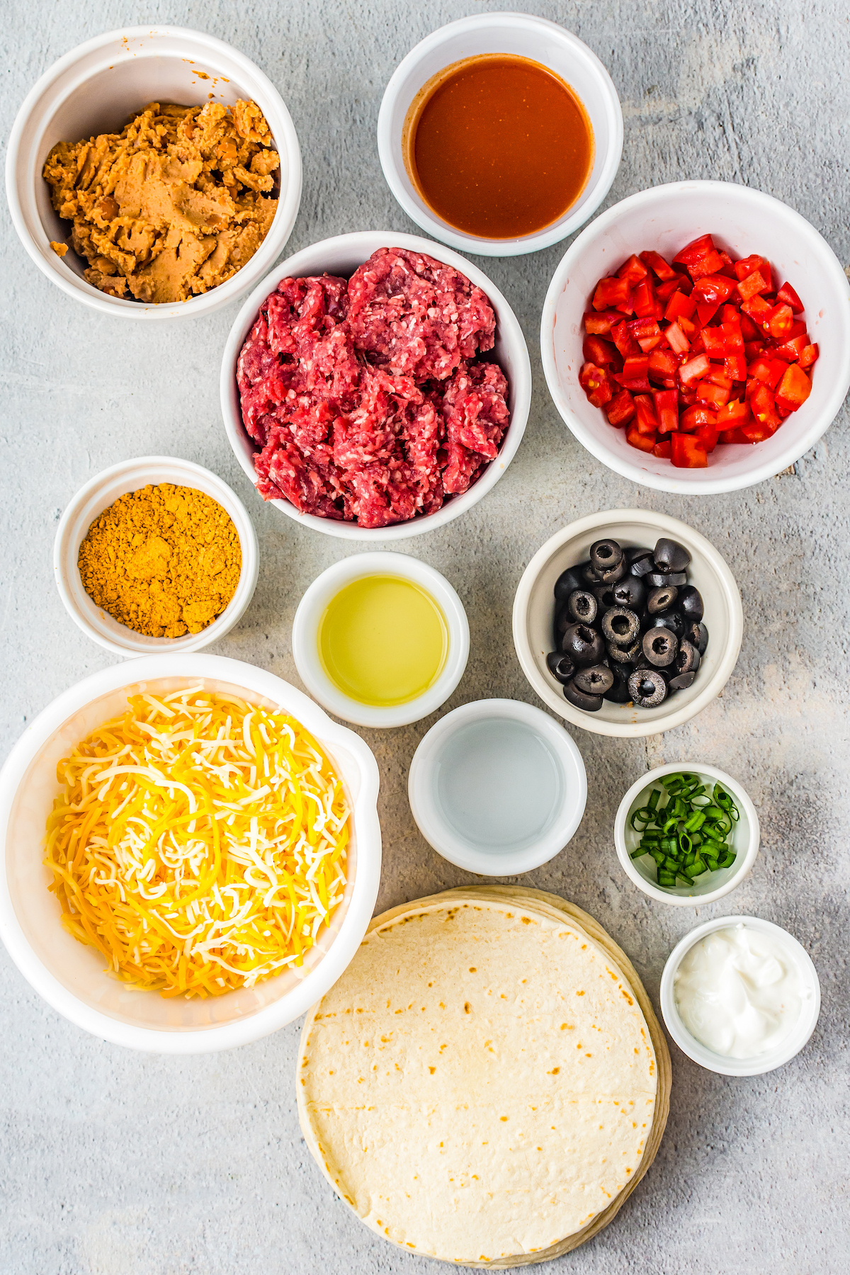 The ingredients for homemade Mexican pizzas, measured and arranged on a cutting board.