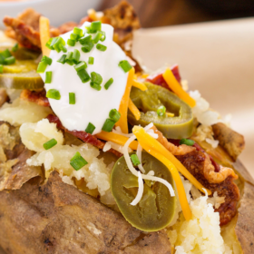 Baked potato loaded with toppings on a plate.