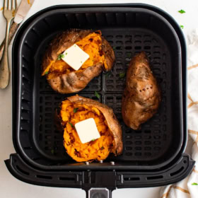 Three sweet potatoes in an air fryer basket.