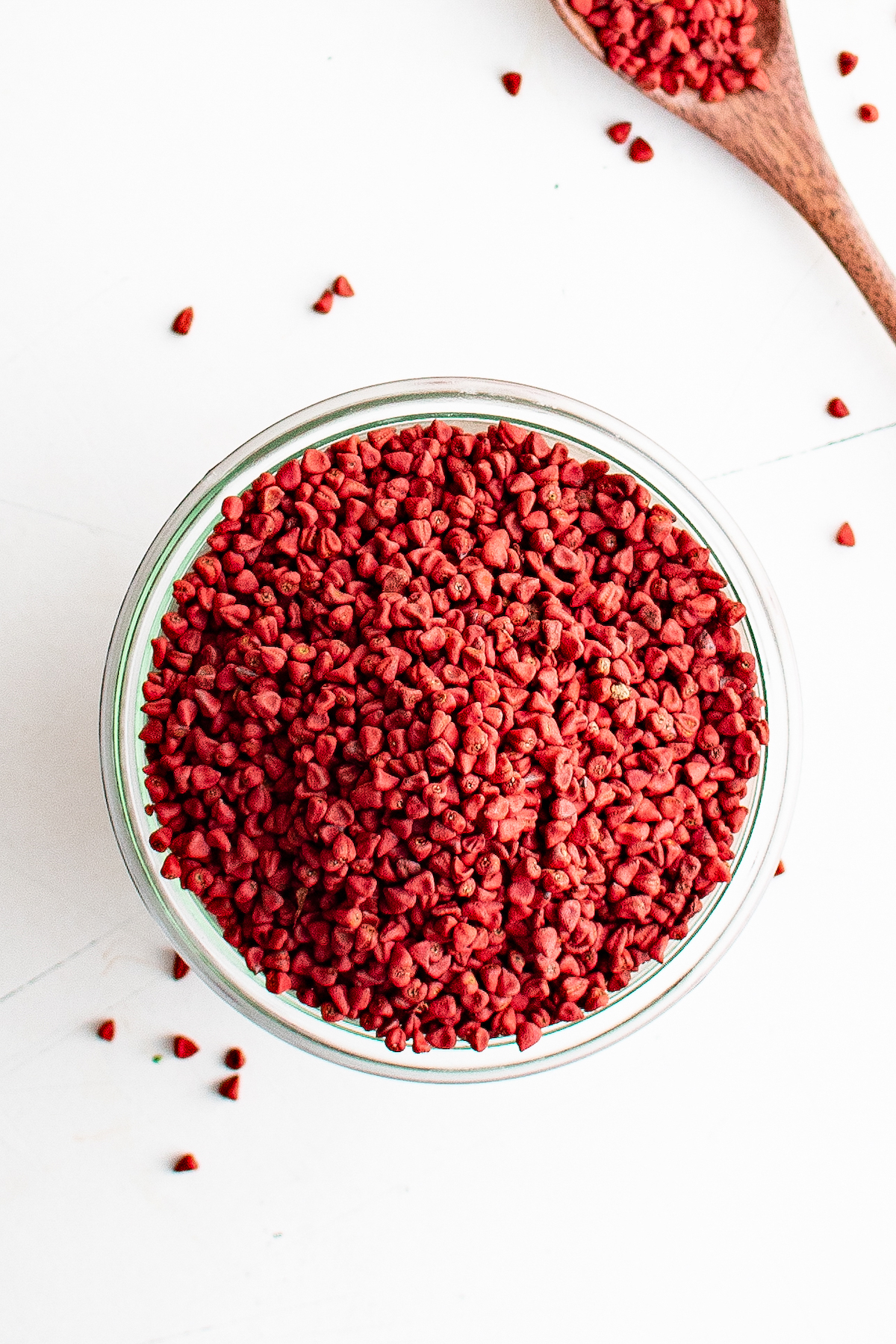 A bowl with Annatto Seeds and a few spilling out the sides.