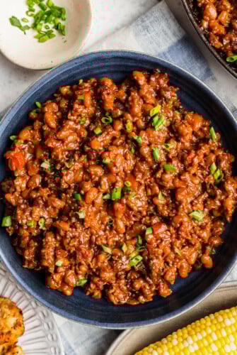 A skillet of homemade baked beans topped with chopped green onion.