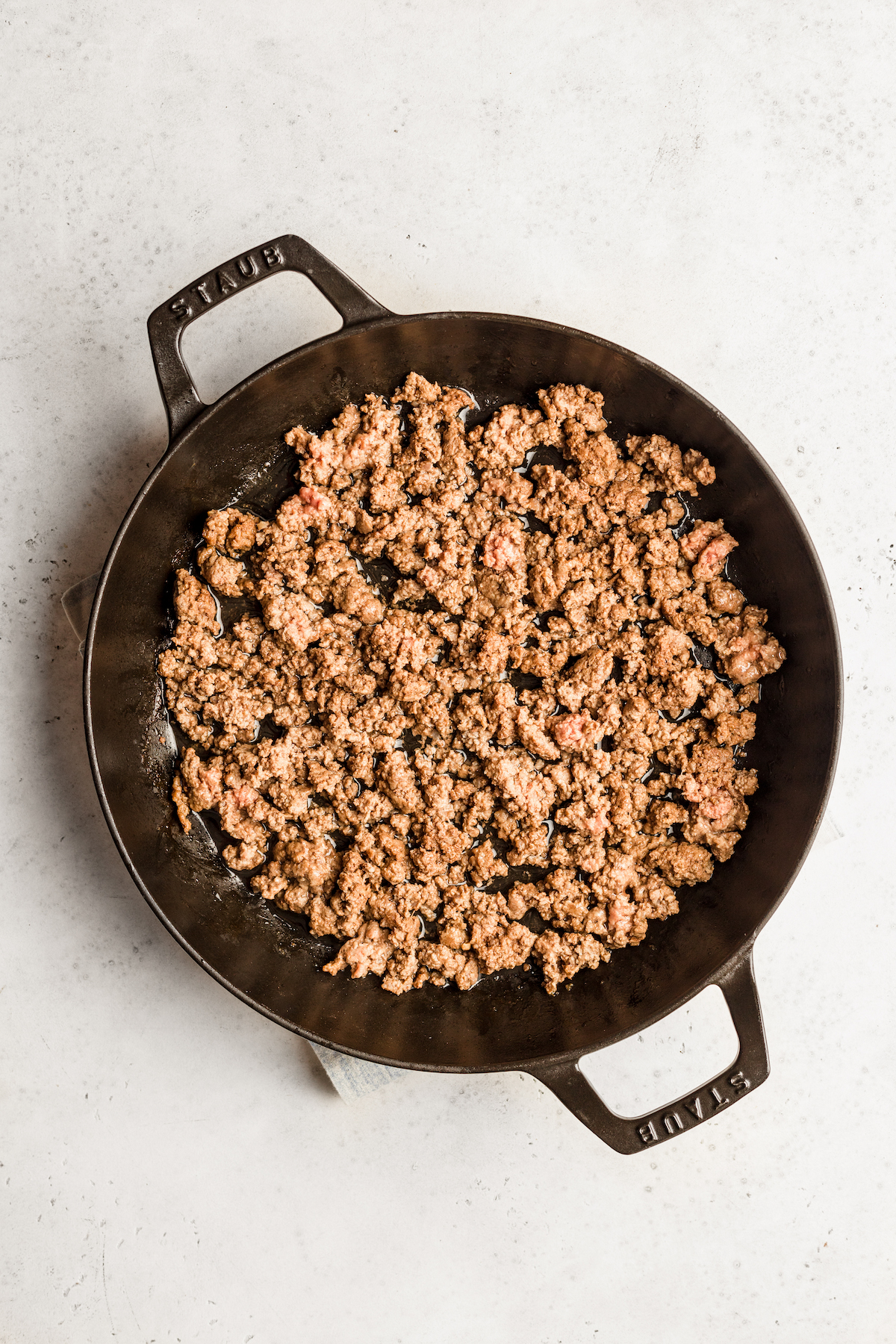 Cooked ground beef in a double-handled skillet.