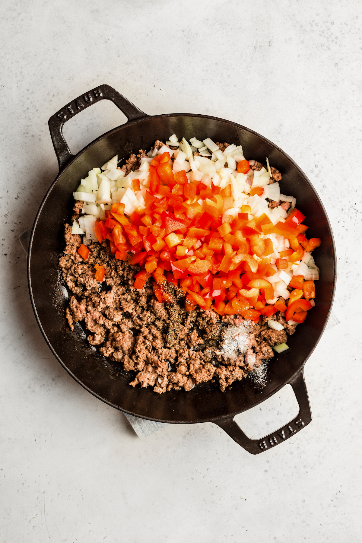 Ground beef and veggies in a two-handled skillet.