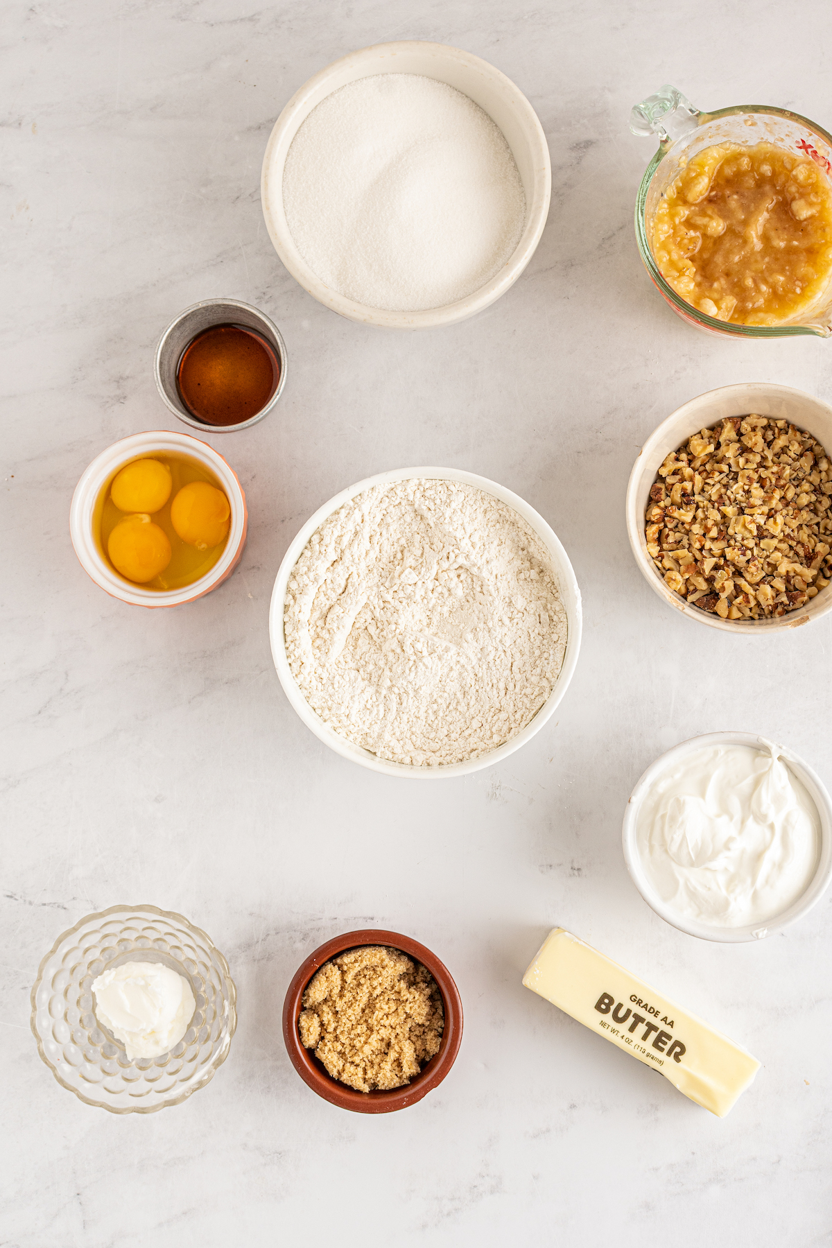 Dry baking ingredients mixed together in a bowl. Wet ingredients are arranged around the mixing bowl.