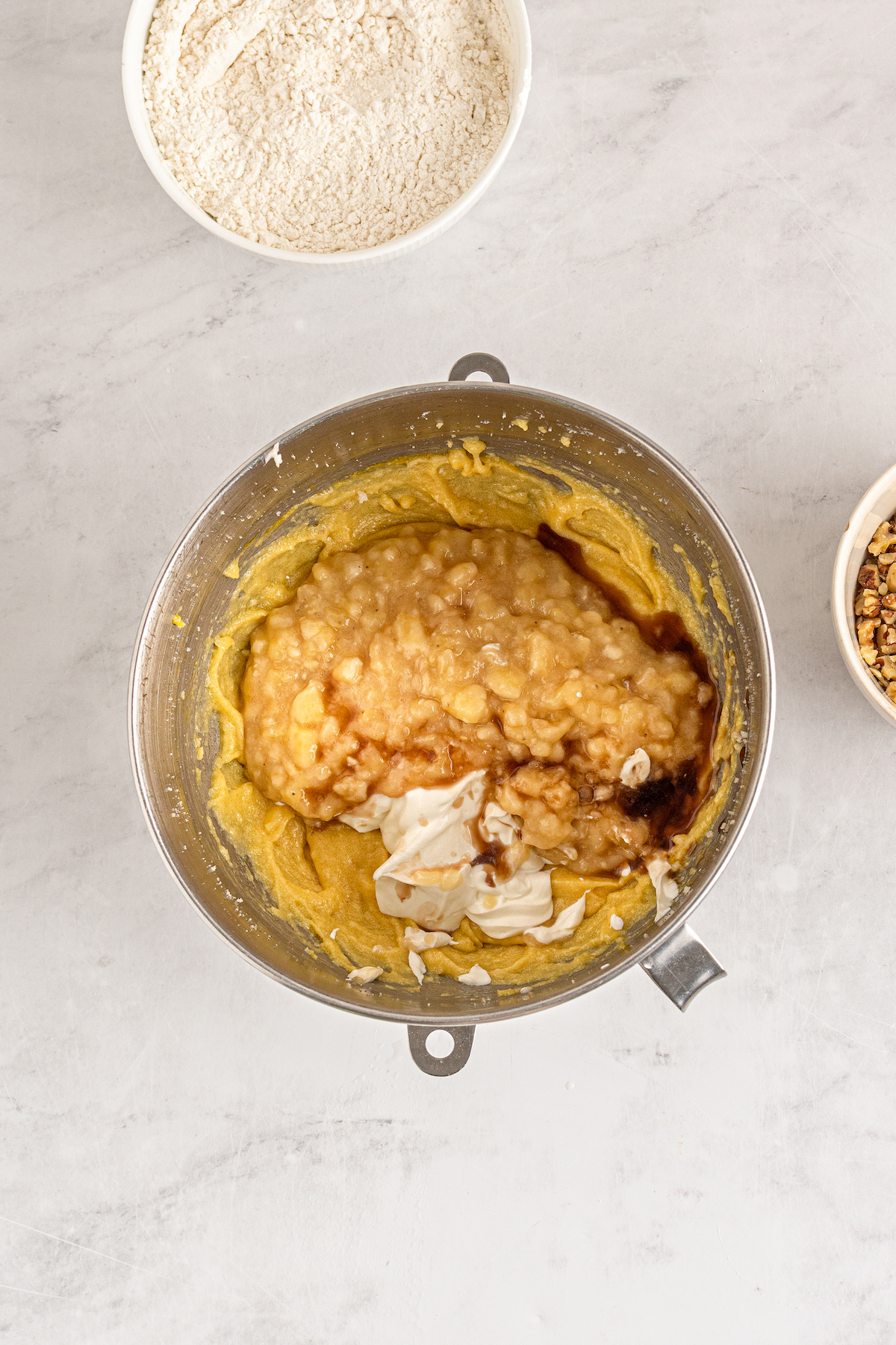 Mashed bananas, sour cream, and other ingredients in a mixing bowl.